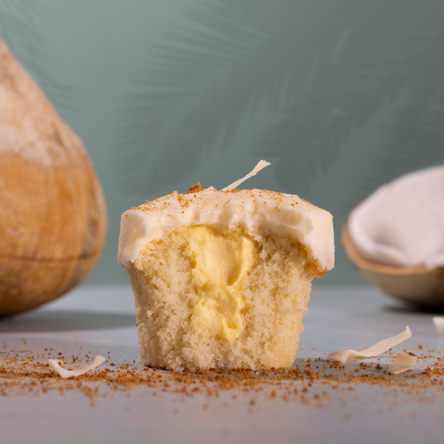 bite of coconut cream pie with coconuts in the background. Coconut cream pie has fluffy coconut cake filled with velvety vanilla custard, topped with silky coconut frosting, and finished with a golden curl of toasted coconut. not-bg