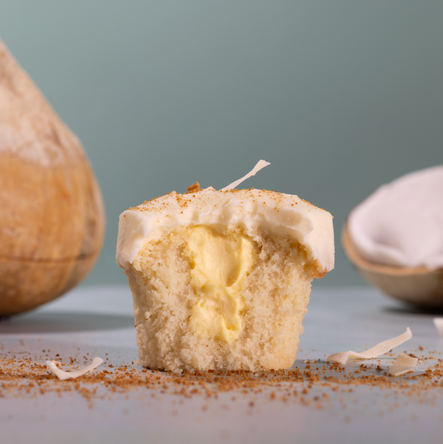 bite of coconut cream pie cupcake with coconut in the background