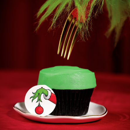 red velvet cupcake topped with green frosting and a grinch decoration