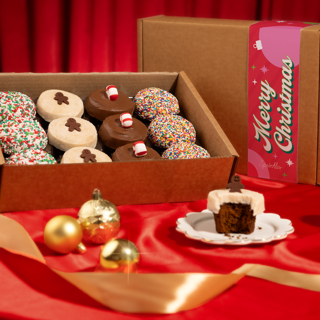 Holiday Assorted Dozen box on a red tablecloth with gold ornaments.