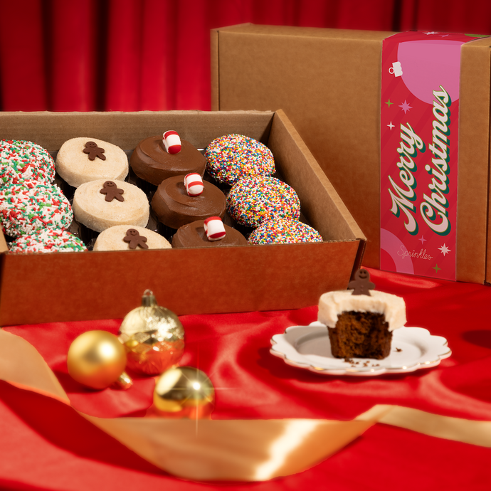 Holiday Assorted Dozen box on a red tablecloth with gold ornaments.
