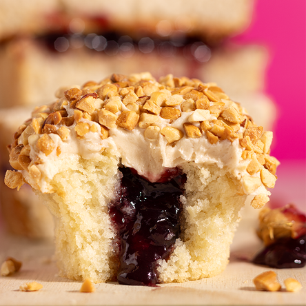 PB&J cupcake bite. Soft vanilla cake, grape jam core, peanut butter cream cheese frosting, and a crushed peanut crunch.