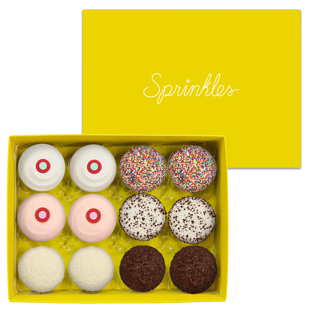 Assorted Dozen Yellow Box includes 2 Red Velvet, 2 Strawberry, 2 Vanilla, 2 Sprinkles, 2 Black & White, and 2 Dark Chocolate cupcakes.