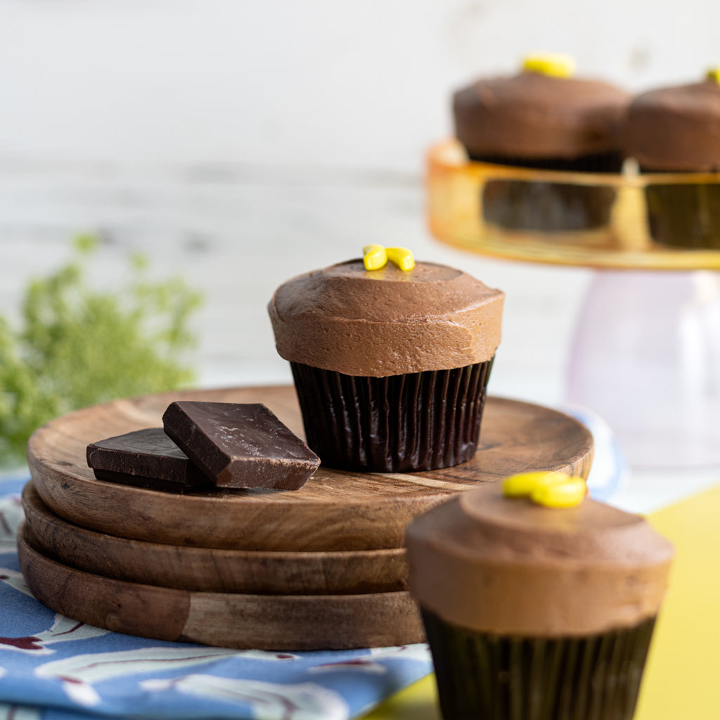 banana dark chocolate cupcakes on top of a stack of wooden plates not-bg