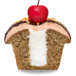 side view of half of a banana split cupcake with banana cake, marshmallow filling, and strawberry frosting, that has been dipped in ganache and finished with crushed peanuts and a maraschino cherry not-bg