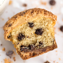 Load image into Gallery viewer, overhead view of cookie cupcake cut in half with a cookie crust lining, chocolate chip studded yellow cake and brown sugar frosting dusted with cookie crumbles not-bg
